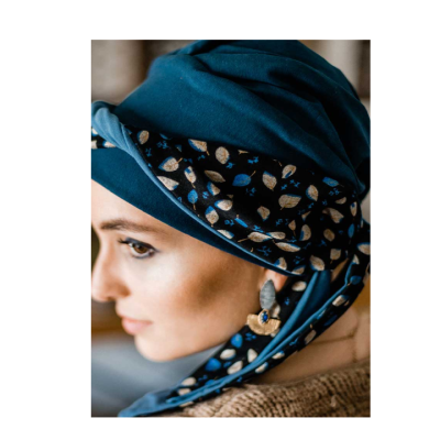 Mulher com turbante azul escuro com padrão de folhas e brincos pendentes