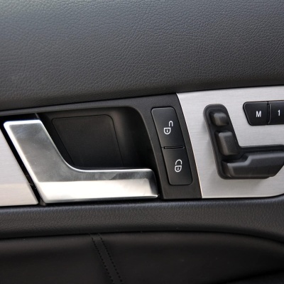 Painel interior de porta de carro com puxador metalizado e botões para bloqueio e ajuste de assento