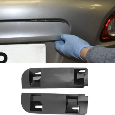 Peça de carro preta sendo segurada por mão com luva azul e duas peças pretas de plástico para automóvel