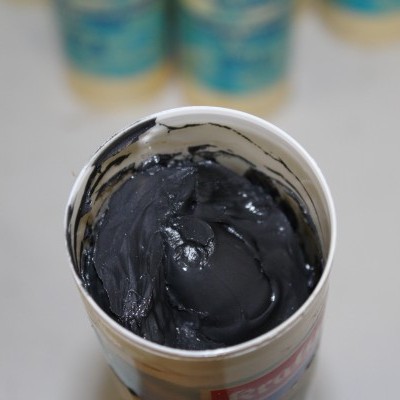 Frasco aberto de tinta preta cremosa com outros frascos ao fundo