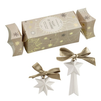 Decoração com duas estrelas brancas cerâmicas com fitas douradas e embalagem temática de estrelas.