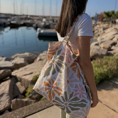 Saco de tecido com padrão floral colorido ao ombro junto a um porto