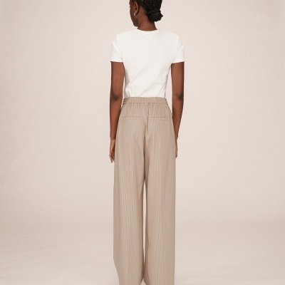 Calças largas bege com riscas e t-shirt branca vista de costas