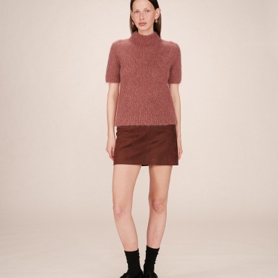 Mulher com camisola rosa de malha e saia castanha
