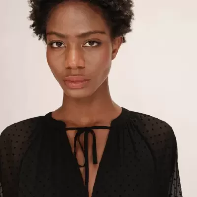 Blusa preta de tecido fino com bolinhas e laço no decote