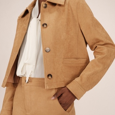 Casaco curto camel efeito camurça com botões castanhos, camisa branca com laço e saia camel com bolso