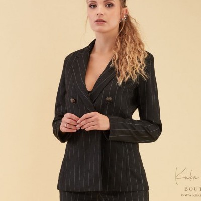 Blazer feminino preto riscas brancas usado por mulher, fundo bege claro.