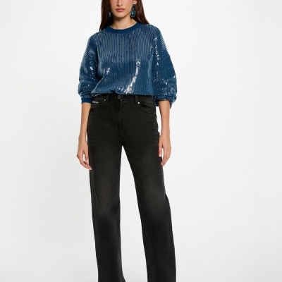 Mulher com camisa de malha azul cintilante e calças pretas de ganga