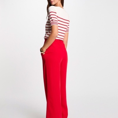 Mulher com camisola de riscas vermelhas e brancas e calças vermelhas largas
