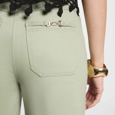 Calças verde-clarinho com bolsa traseira e fecho metálico dourado decorativo