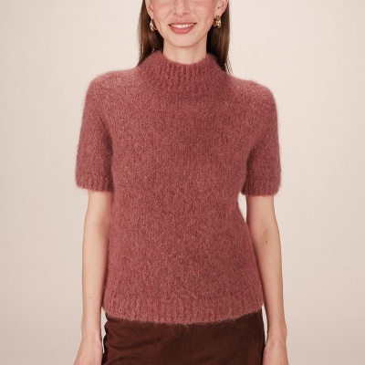 Mulher a usar camisola rosa felpuda de malha com gola alta e mangas curtas