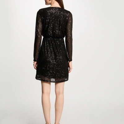 Vestido preto curto com lantejoulas, visto de costas e sandálias creme