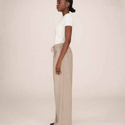 Calças caneladas bege com cordão, t-shirt branca e sapatos pretos em modelo feminina.