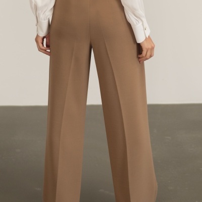 Calças castanhas largas e camisa branca vista de costas