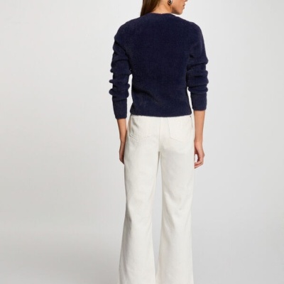 Mulher de costas com camisola azul escura e calças brancas largas