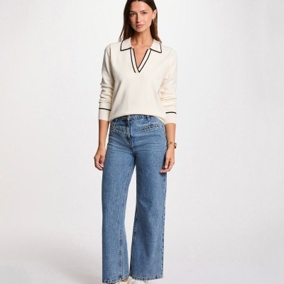 Modelo feminina a usar sweater branco e calças de ganga azul