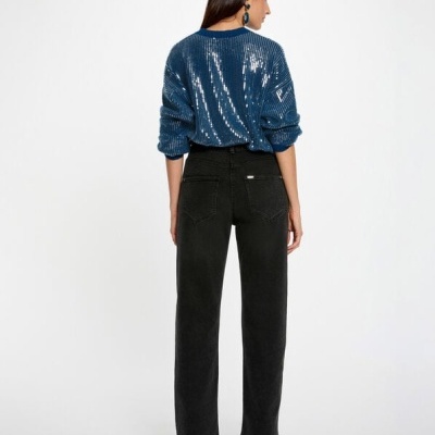 Mulher com camisola azul cintilante e calças denim pretas vista de costas