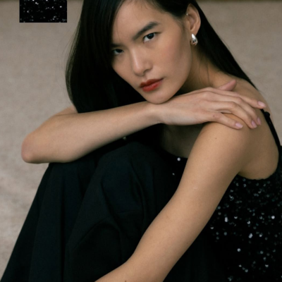 Top preto com lantejoulas usado por mulher com cabelo preto e calças pretas.