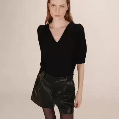 Mulher com blusa preta de manga média e calções pretos de pele sintética