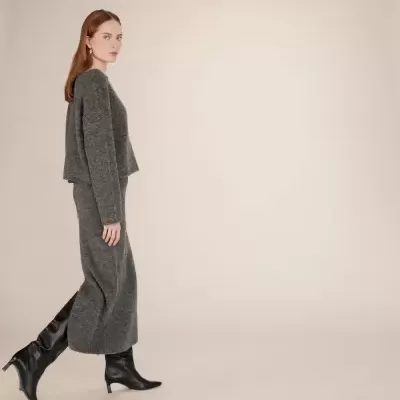 Mulher com conjunto de malha cinzenta e botas pretas