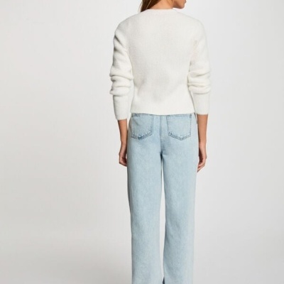 Pessoa de costas com camisola branca e calças de ganga largas azuis claras.