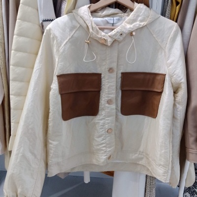 Casaco branco com bolsos marrons pendurado num cabide de madeira com coração recortado