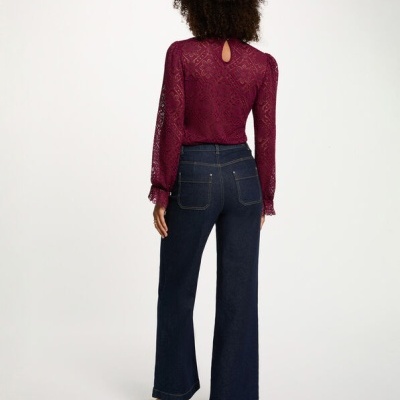 Calças de ganga azuis escuras e blusa de renda borgonha vistas de costas