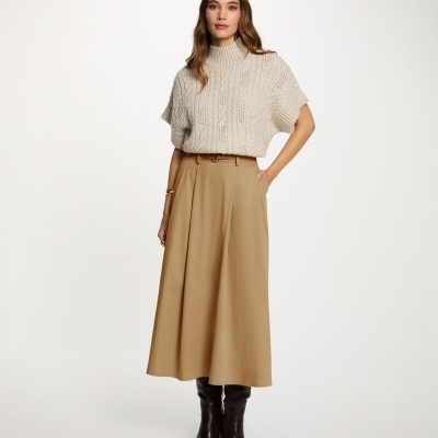 Mulher com camisola de malha bege, saia comprida bege e botas castanhas escuras