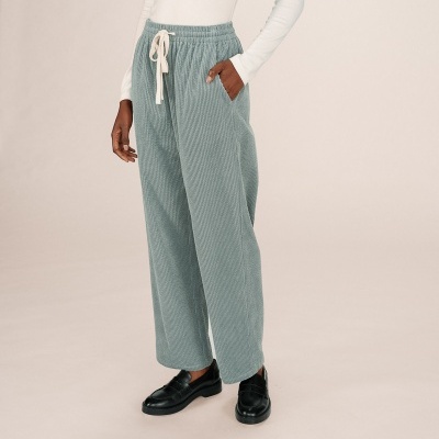 Calças cinzentas de tecido riscado com cordão na cintura, camisa branca e sapatos pretos.