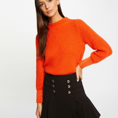 Mulher com camisola laranja e saia preta com botões