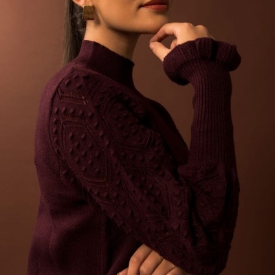 Mulher com camisola castanha escura texturada e brincos dourados