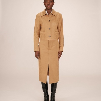 Mulher vestindo casaco bege e saia comprida bege com botas pretas