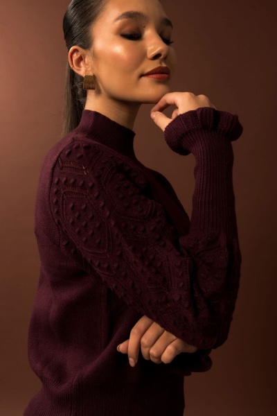 Mulher com camisola castanha escura texturada e brincos dourados