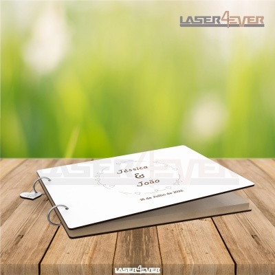 Livro branco com argolas e texto Jéssica & João, sobre mesa de madeira