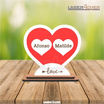 Expositor acrílico em formato de coração com nomes Afonso e Matilde e palavra love numa base branca sobre mesa de madeira
