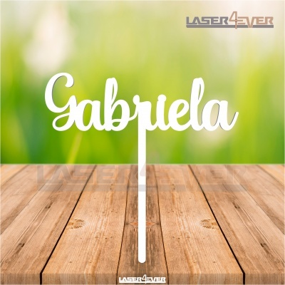 Topo de bolo com o nome Gabriela em acrílico branco sobre mesa de madeira