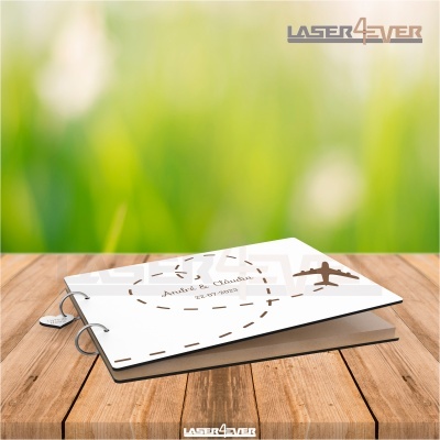 Álbum de fotos branco com desenho de avião e texto Amor de Anjos sobre superfície de madeira