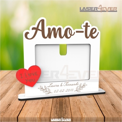 Moldura de foto em branco com texto 'Amo-te' e coração vermelho com 'I LOVE YOU' sobre mesa de madeira.