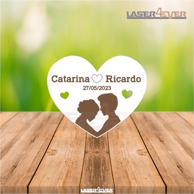 Placa coração branca com texto e silhueta de casal sobre madeira