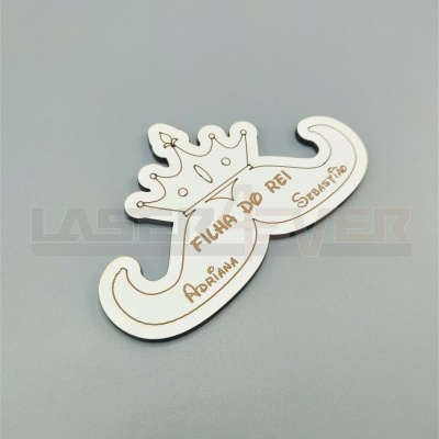 Emblema em madeira branca com coroa e texto gravado 'FILHA DO REI', 'ADRIANA', 'SEBASTIÃO'