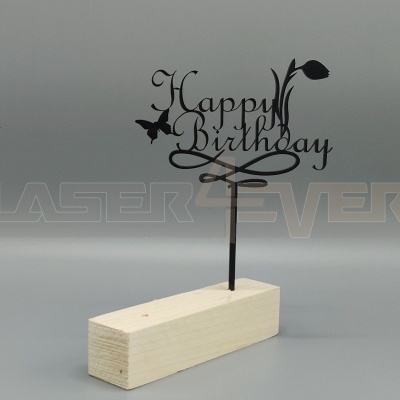 Topper de bolo em metal preto 'Happy Birthday' numa base de madeira clara