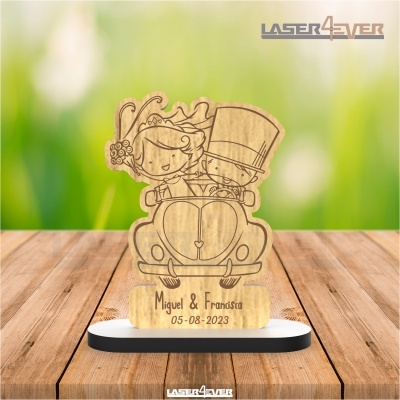 Peça decorativa em madeira com casal de noivos num carro clássico e gravação personalizada.