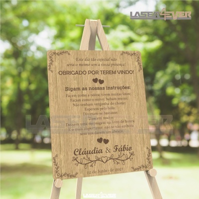 Placa de madeira com texto gravado em português, fixada num cavalete de madeira ao ar livre