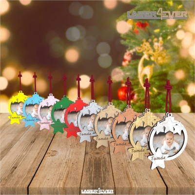 Ornamentos de Natal com nome Tomás em várias cores pendurados em mesa de madeira com árvore de Natal ao fundo