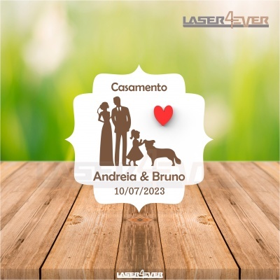 Etiqueta quadrada branca com silhuetas castanhas de casal, criança e cão, coração vermelho e texto de casamento
