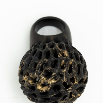 anel negro com topo esférico perfurado e dourado