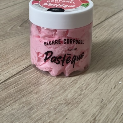 Frasco de creme rosa com tampa branca sobre superfície de madeira