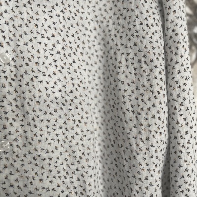 Camisa branca com padrão de pequenas flores pretas e laranjas e botões brancos