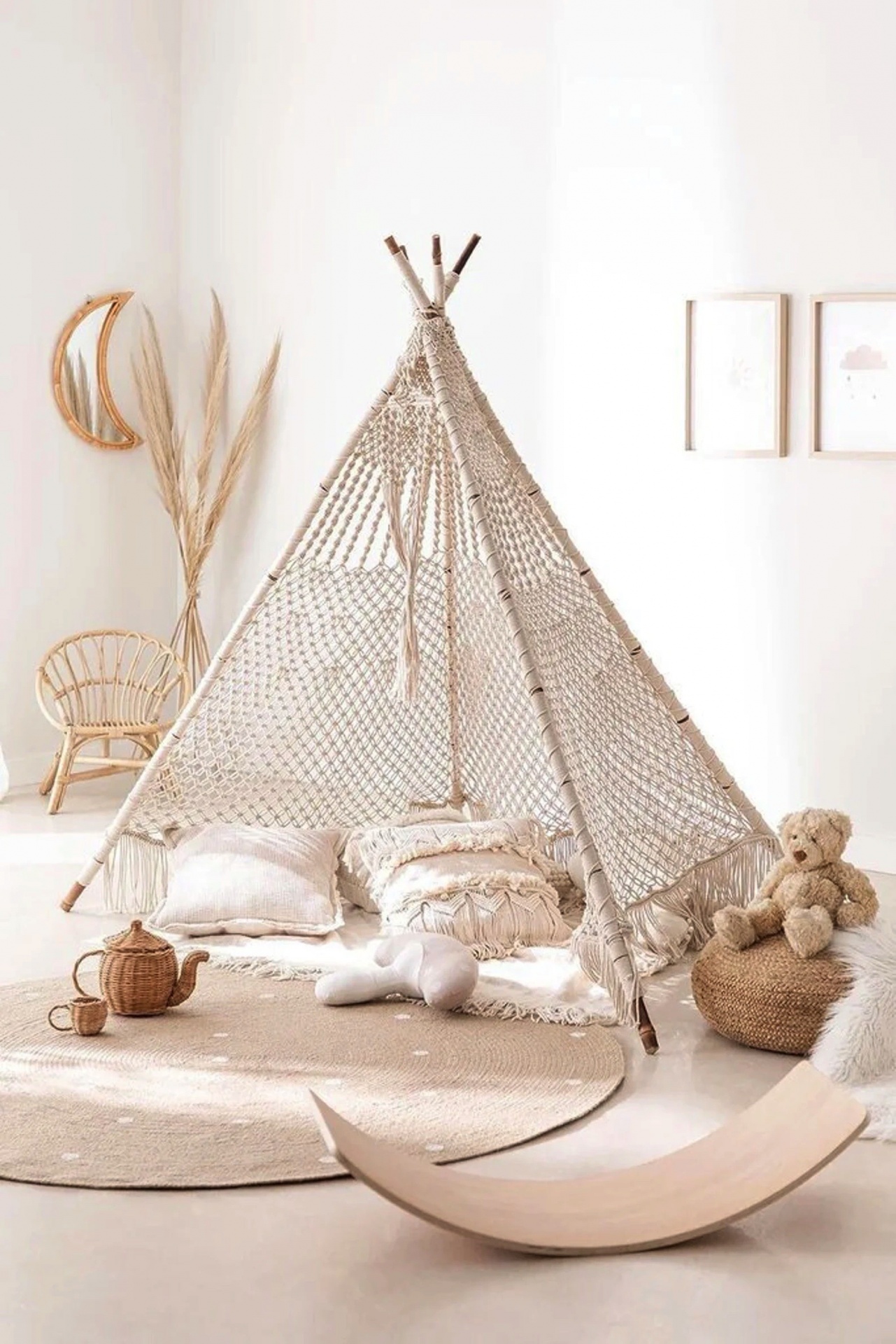 Tenda macramé bege com almofadas, cadeira em vime e ursinho peluche num quarto infantil