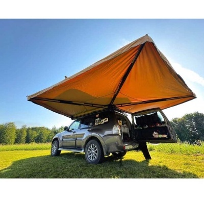 Viatura cinzenta com toldo castanho aberto no campo